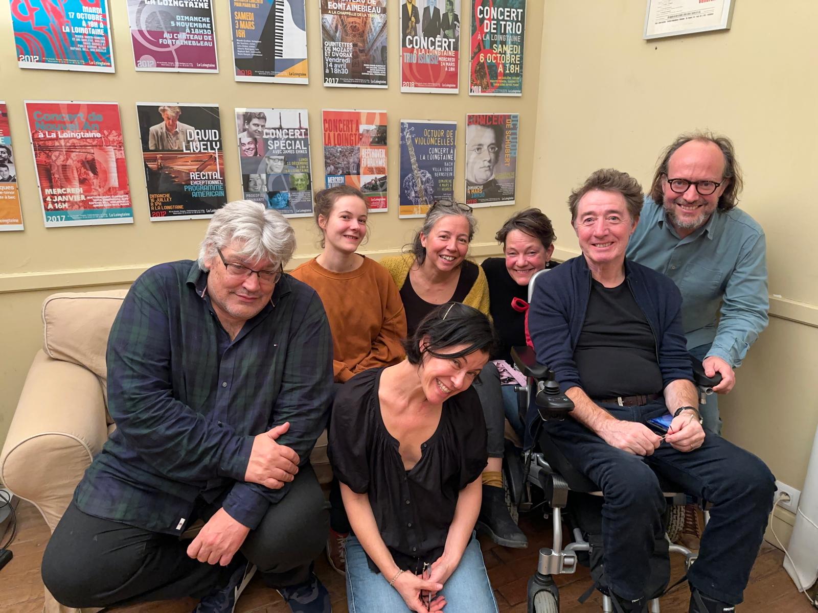 Musiciens et amis réunis dans le salon, devant le mur couvert d’affiches des concerts de La Loingtaine