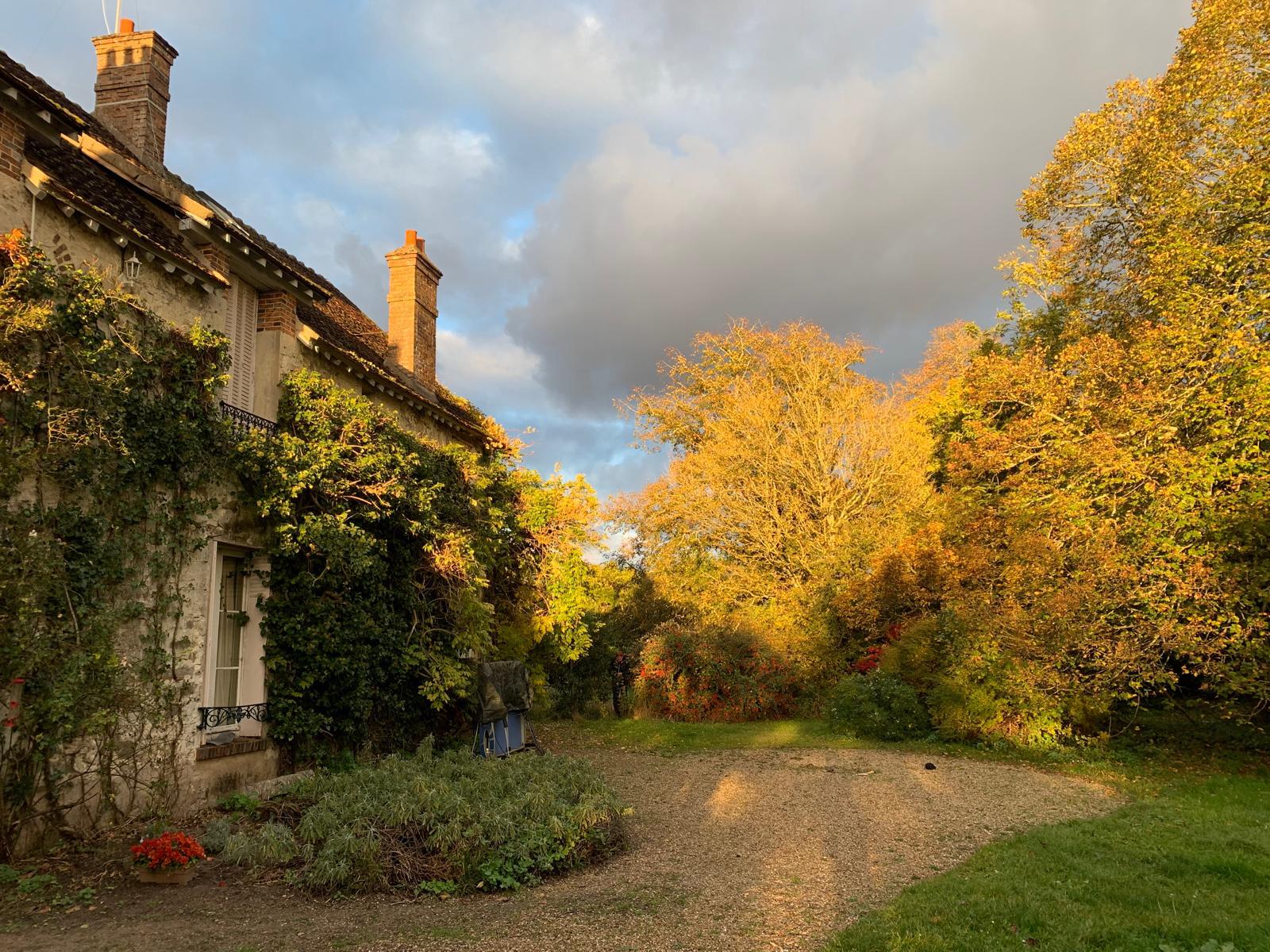 La façade couverte de lierre et la cour de gravier, un soir d’automne