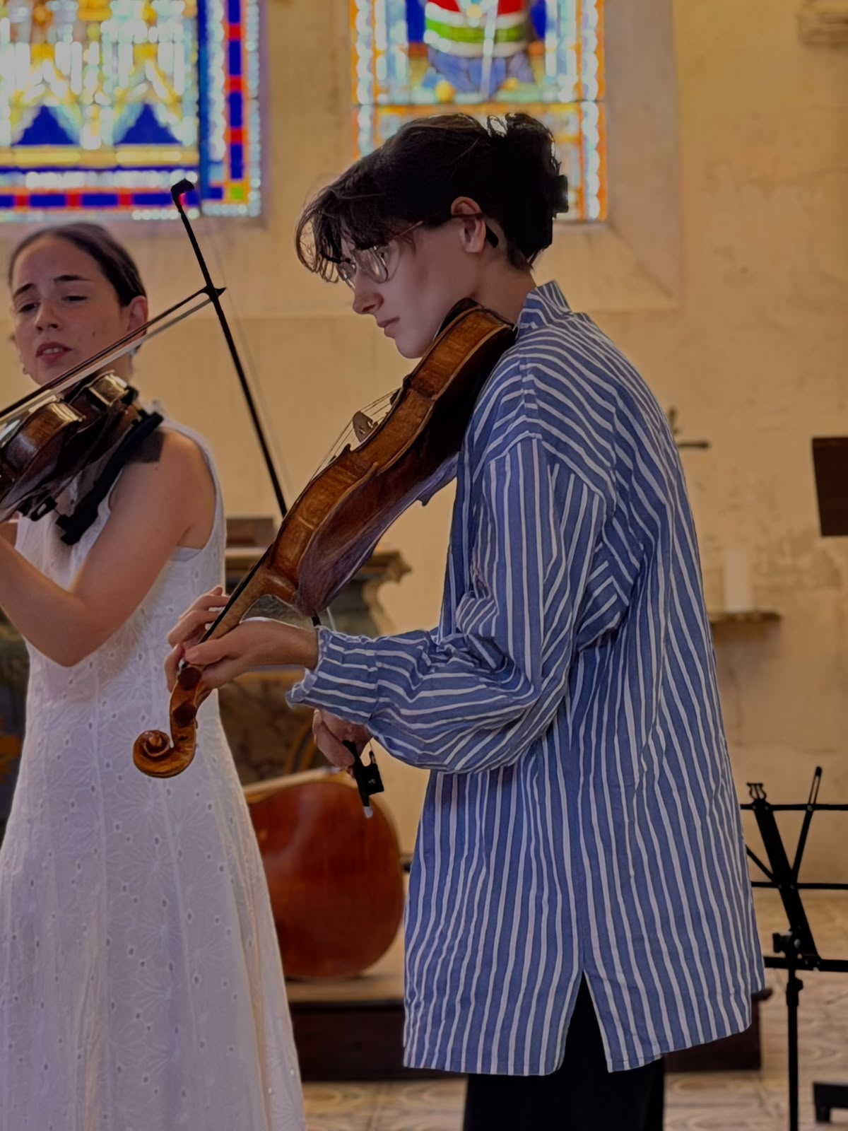 Deux jeunes musiciens jouent devant les vitraux d’une église des environs